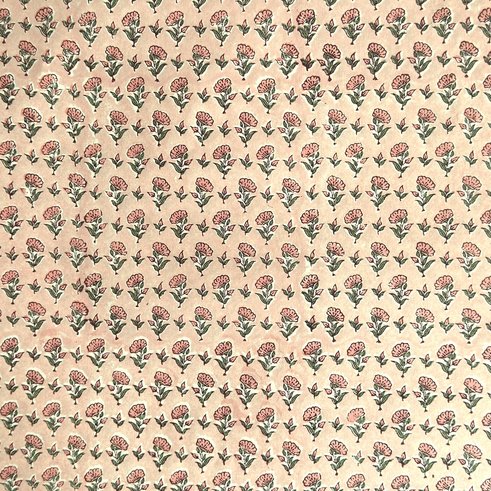 a hand block printed sheet of wrapping paper with a ditsy floral print in pink. Pictured rolled with another design