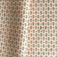 a hand block printed sheet of wrapping paper with a ditsy floral print in pink. Pictured rolled with another design