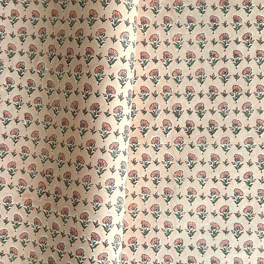 a hand block printed sheet of wrapping paper with a ditsy floral print in pink. Pictured rolled with another design