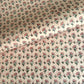 a hand block printed sheet of wrapping paper with a ditsy floral print in pink. Pictured rolled with another design