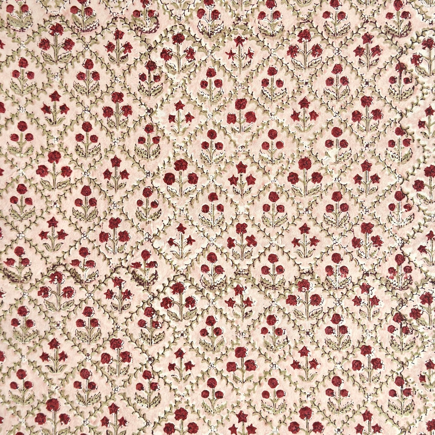 a sheet of hand block printed paper with a floral trellis design in blush pink, sage green and deep red