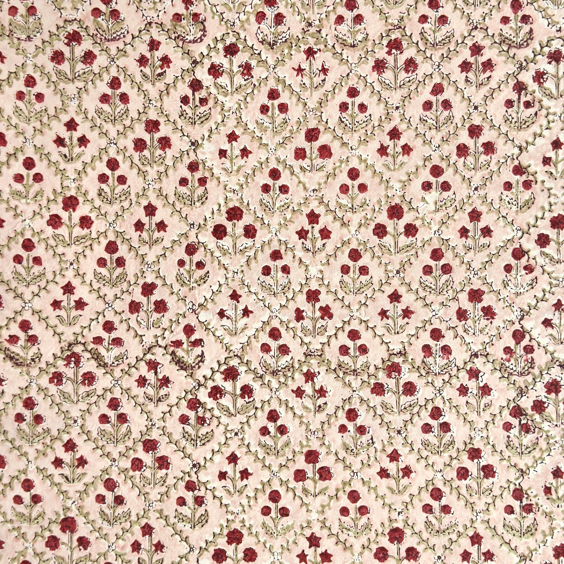 a sheet of hand block printed paper with a floral trellis design in blush pink, sage green and deep red