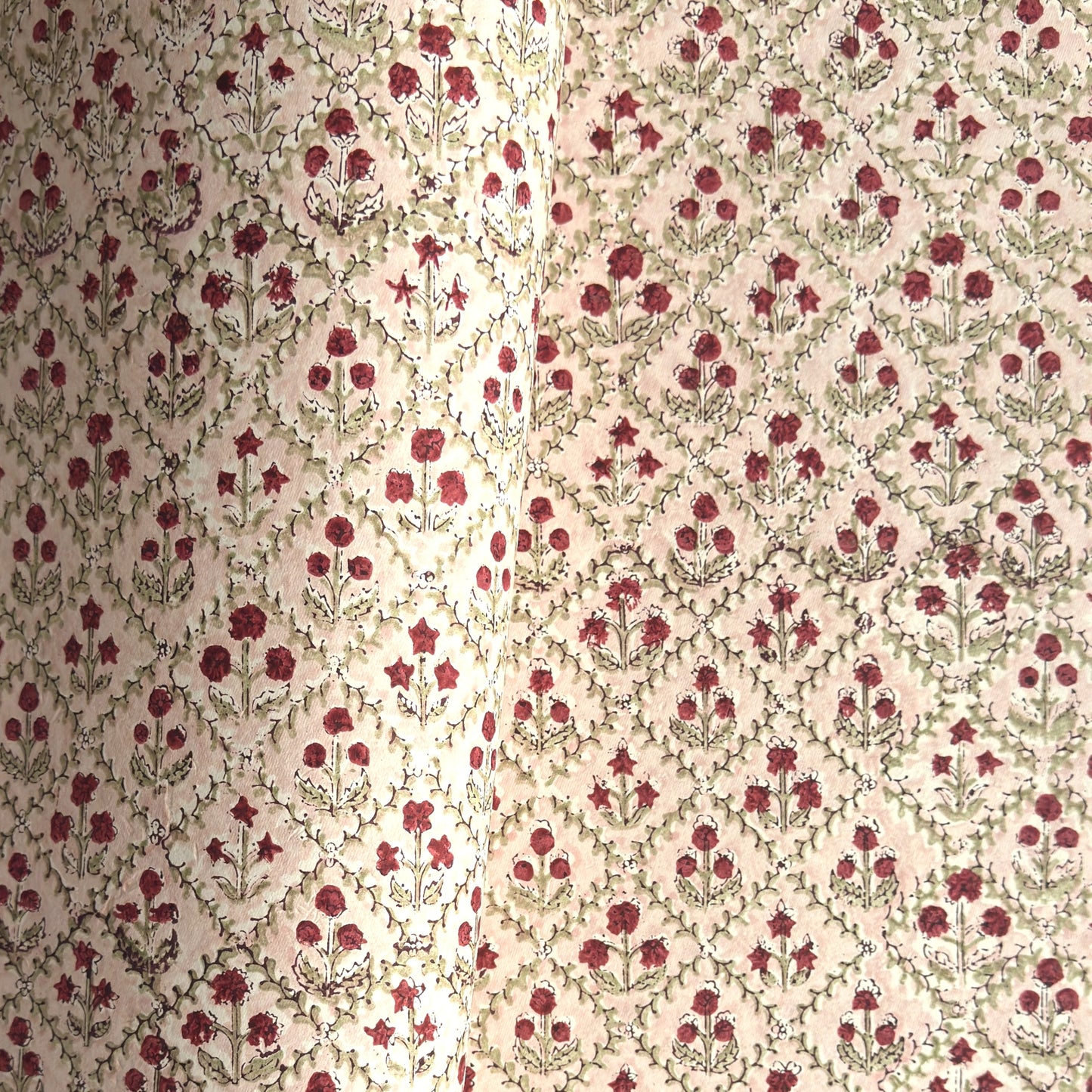 a sheet of hand block printed paper with a floral trellis design in blush pink, sage green and deep red