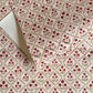 a sheet of hand block printed paper with a floral trellis design in blush pink, sage green and deep red