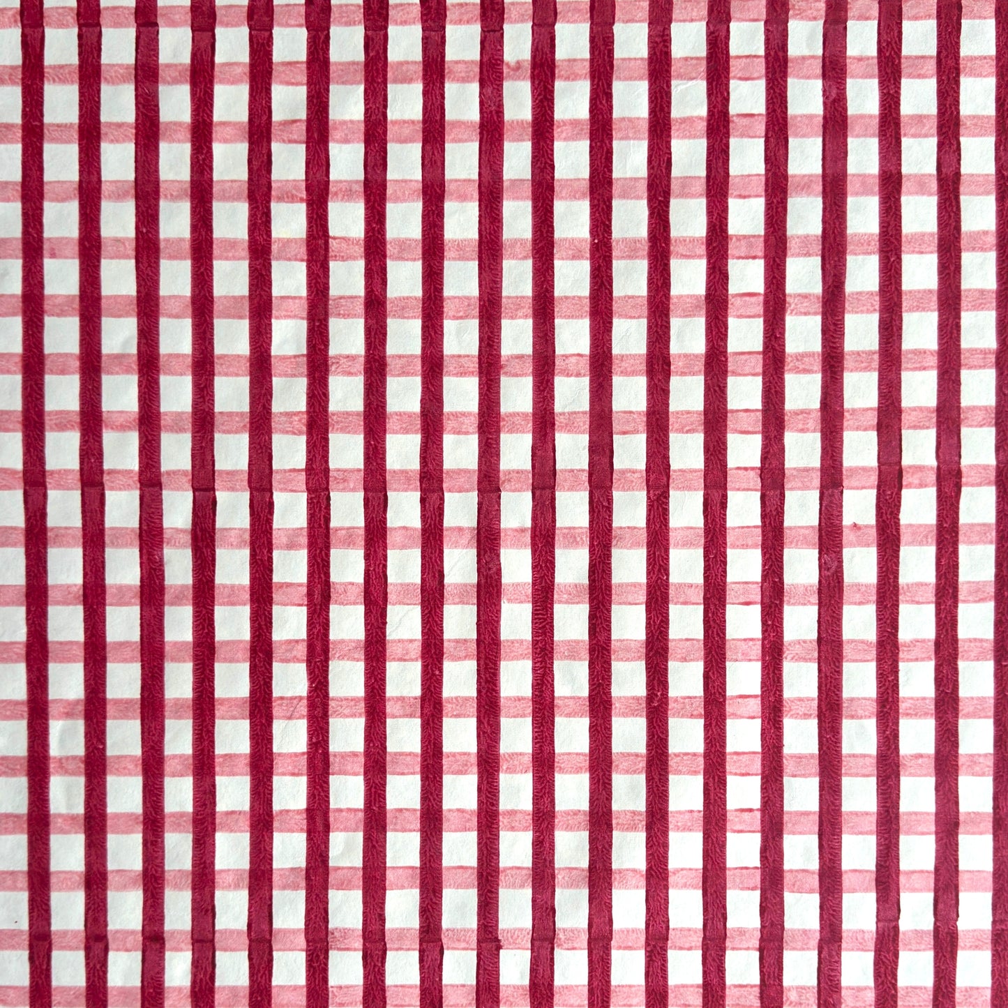 red and pink gingham pattern hand block printed on a white sheet of cotton paper
