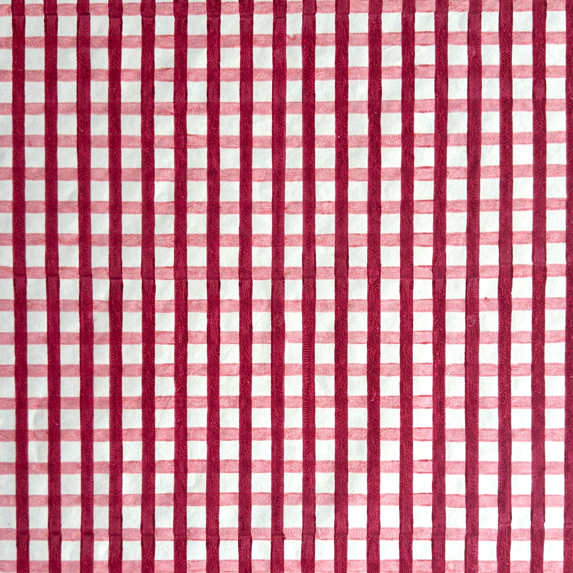 red and pink gingham pattern hand block printed on a white sheet of cotton paper