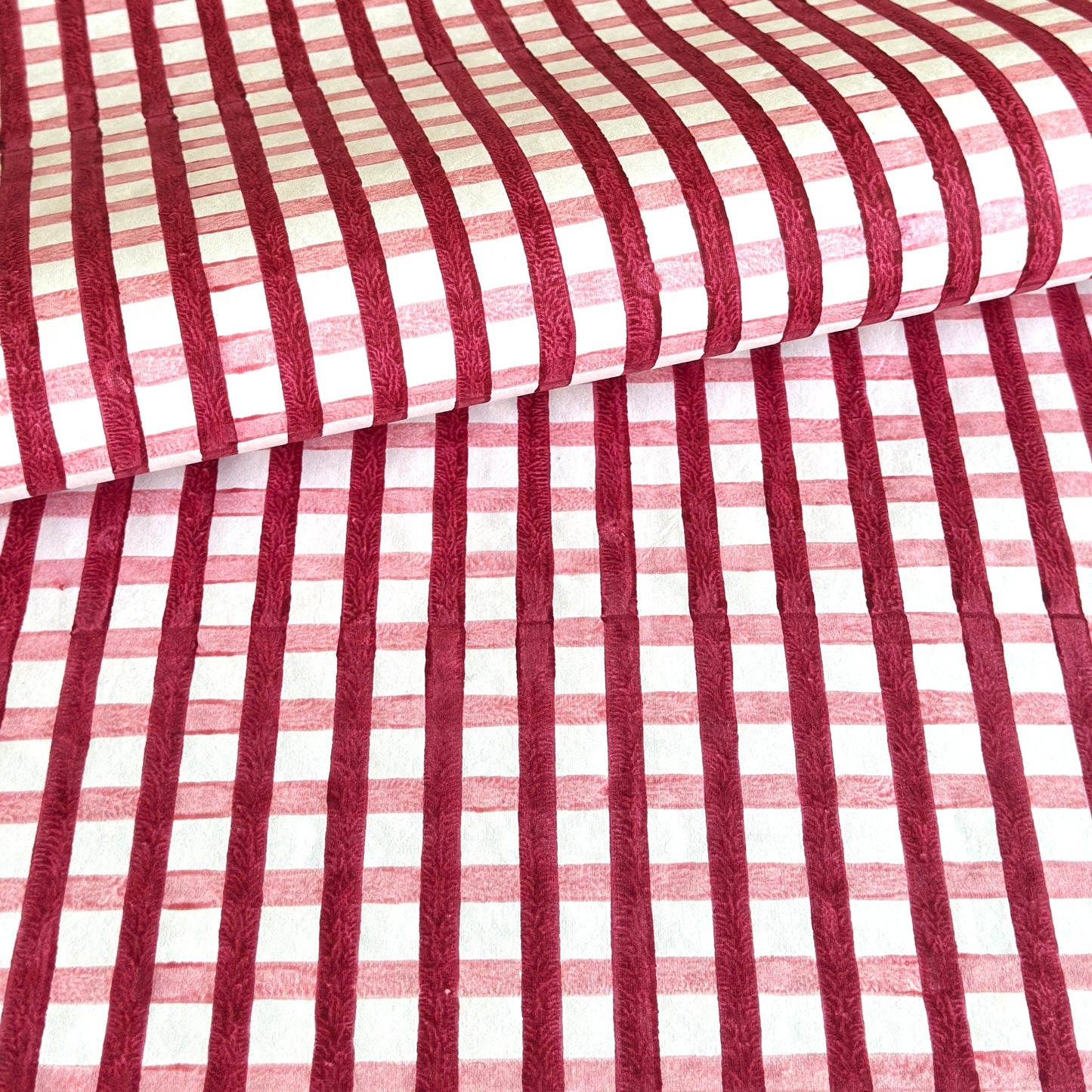 red and pink gingham pattern hand block printed on a white sheet of cotton paper