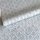 a sheet of hand block printed wrapping paper with a floral lattice design in soft blue