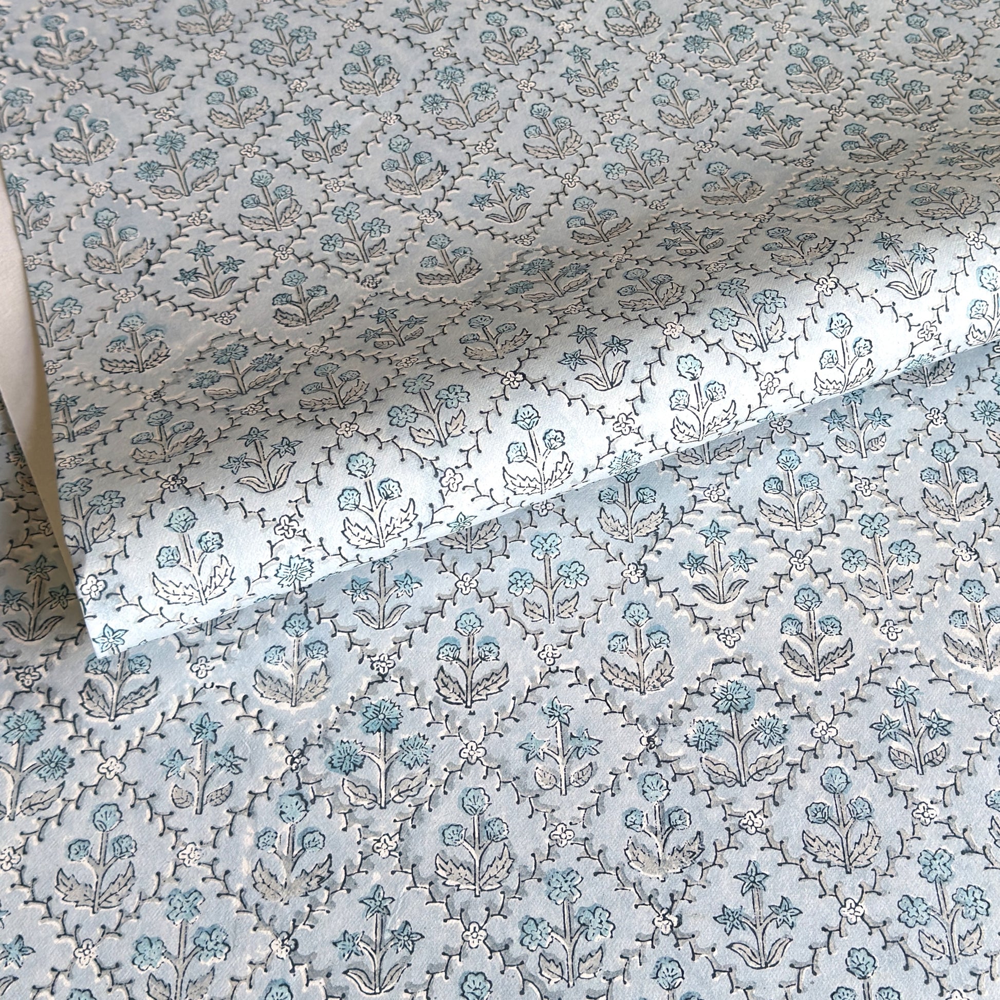 a sheet of hand block printed wrapping paper with a floral lattice design in soft blue