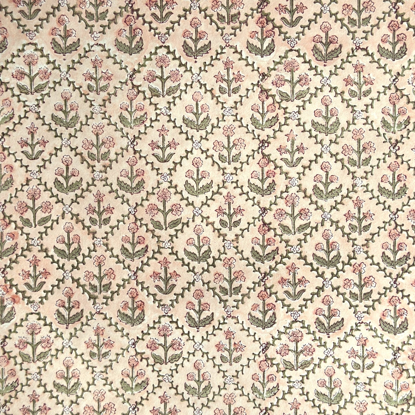 a sheet of hand block printed wrapping paper with a floral trellis design in coral pink and sage green