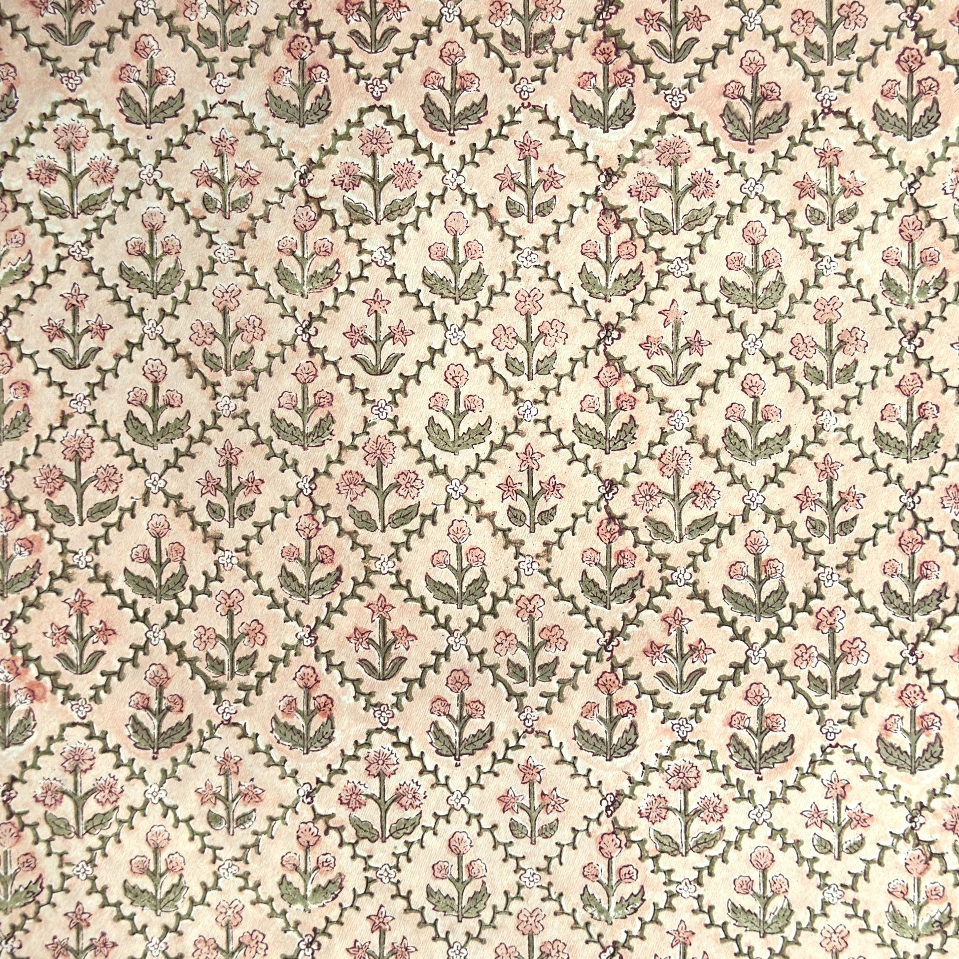 a sheet of hand block printed wrapping paper with a floral trellis design in coral pink and sage green