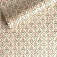 a sheet of hand block printed wrapping paper with a floral trellis design in coral pink and sage green