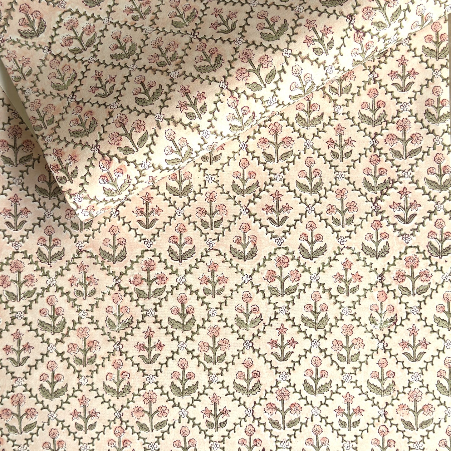 a sheet of hand block printed wrapping paper with a floral trellis design in coral pink and sage green