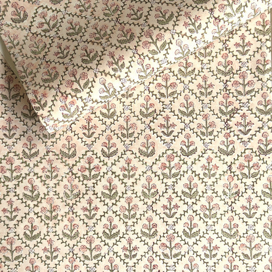 a sheet of hand block printed wrapping paper with a floral trellis design in coral pink and sage green