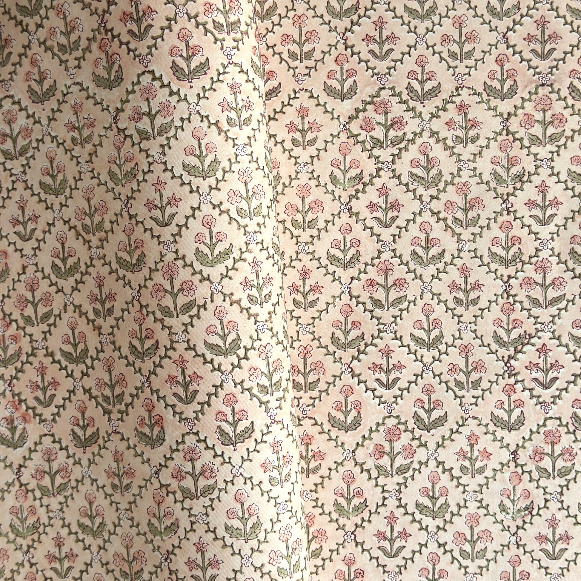a sheet of hand block printed wrapping paper with a floral trellis design in coral pink and sage green
