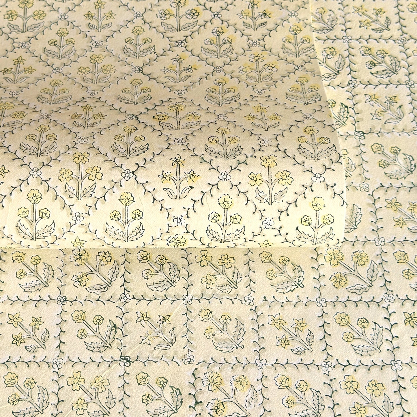 a sheet of hand block printed wrapping paper with a floral lattice design in soft buttermilk yellow