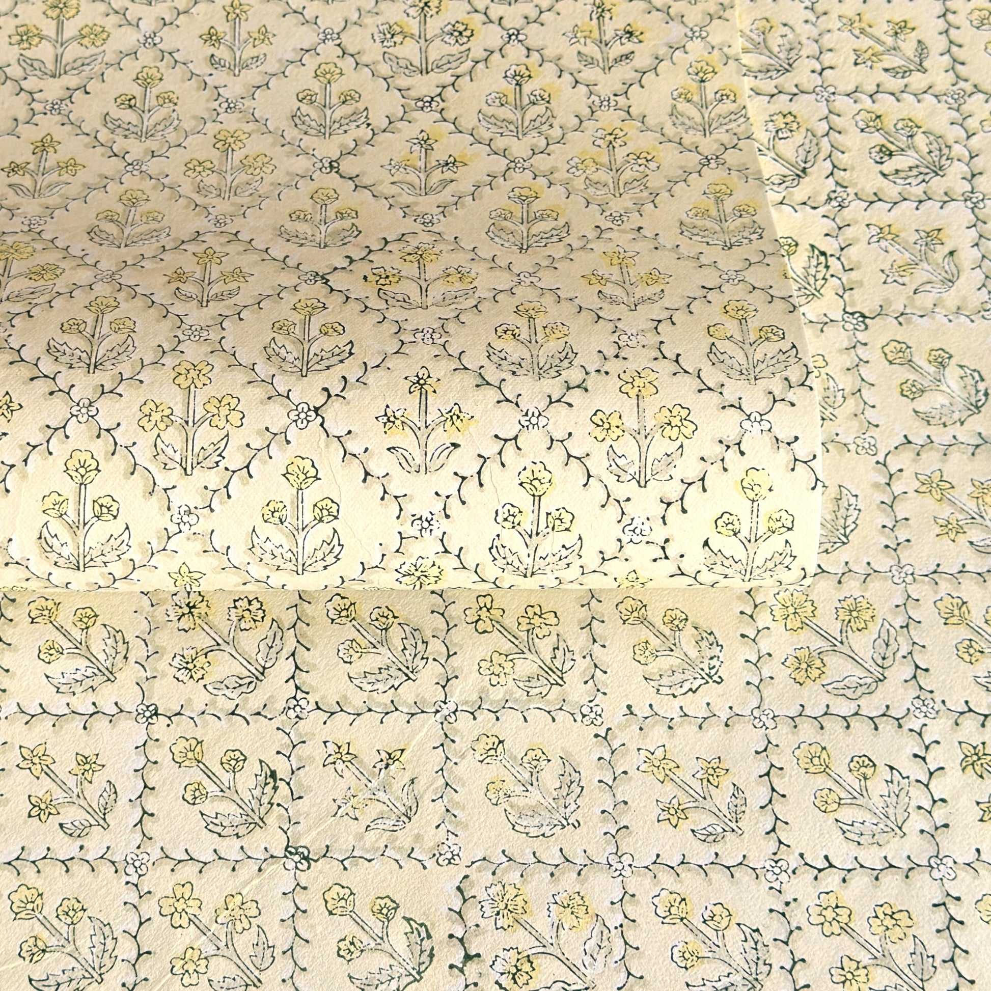 a sheet of hand block printed wrapping paper with a floral lattice design in soft buttermilk yellow