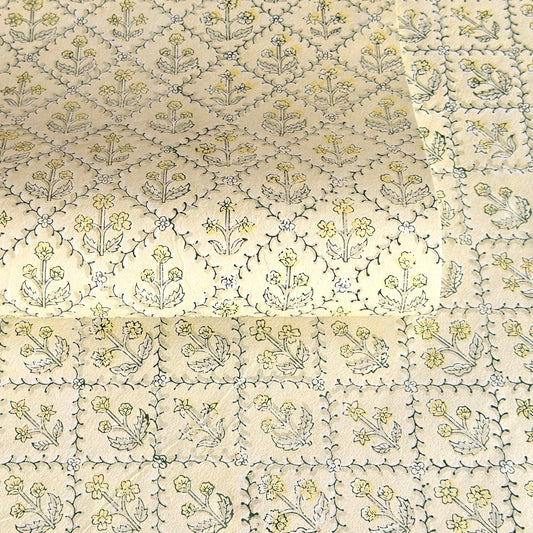 a sheet of hand block printed wrapping paper with a floral lattice design in soft buttermilk yellow