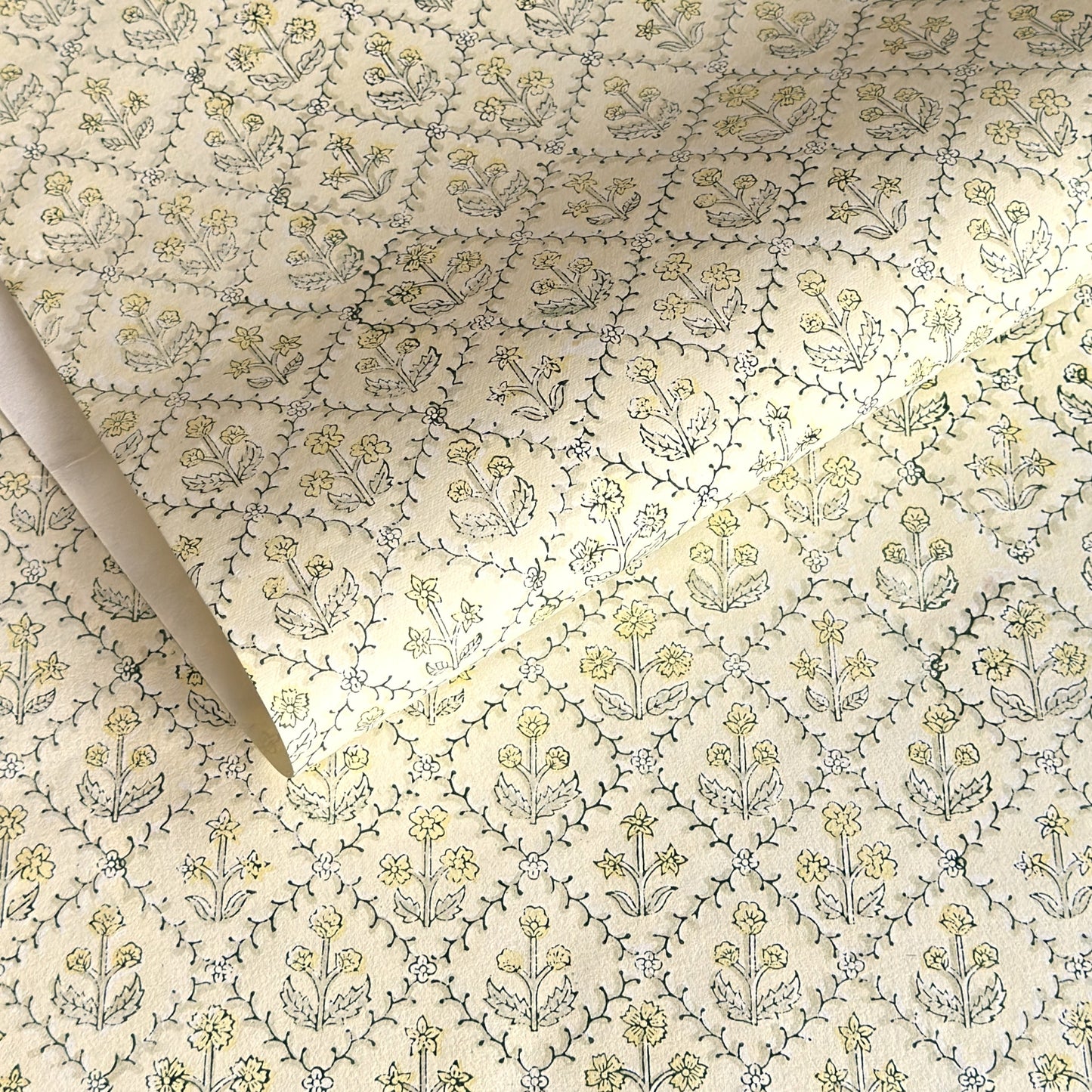 a sheet of hand block printed wrapping paper with a floral lattice design in soft buttermilk yellow