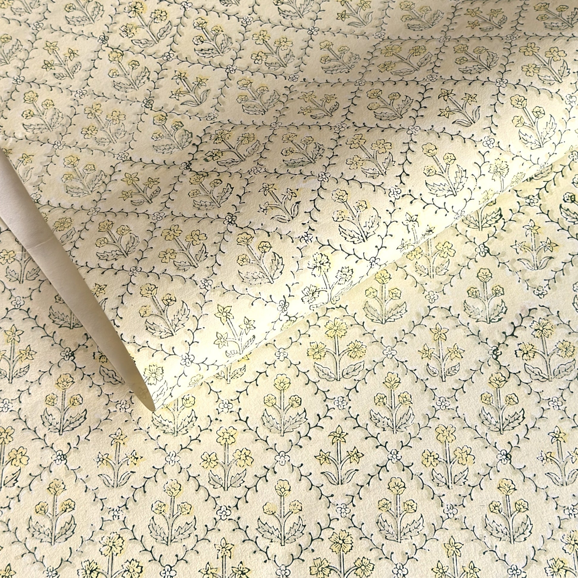 a sheet of hand block printed wrapping paper with a floral lattice design in soft buttermilk yellow