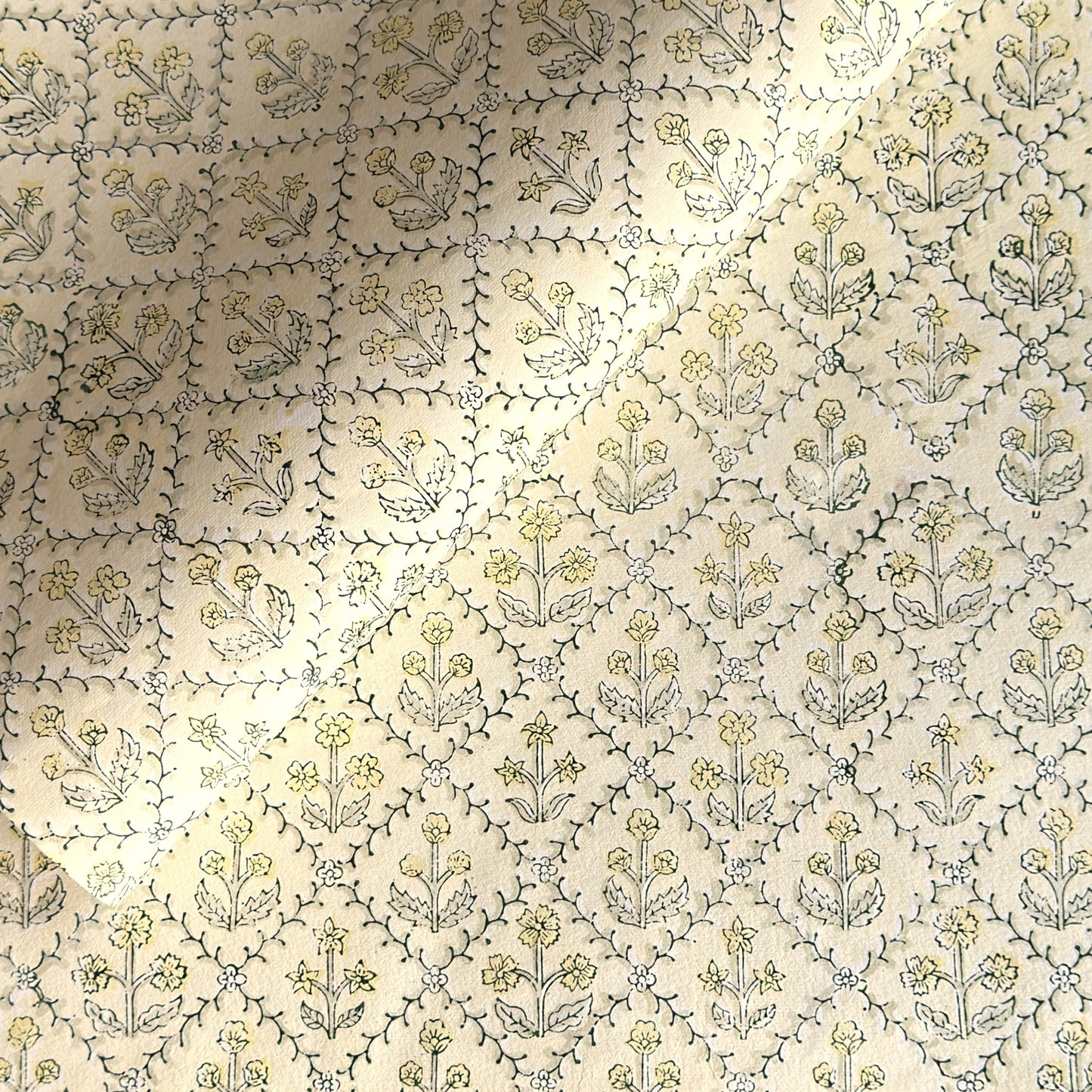 a sheet of hand block printed wrapping paper with a floral lattice design in soft buttermilk yellow