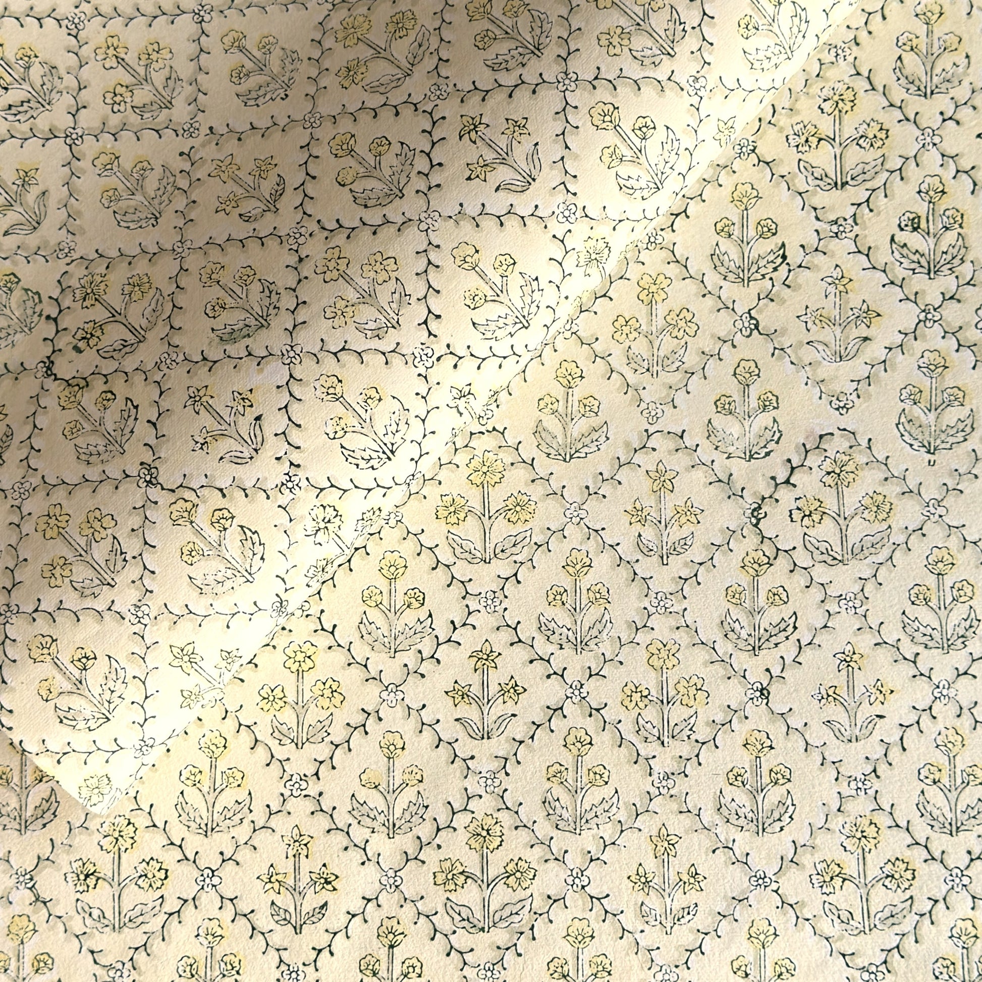 a sheet of hand block printed wrapping paper with a floral lattice design in soft buttermilk yellow
