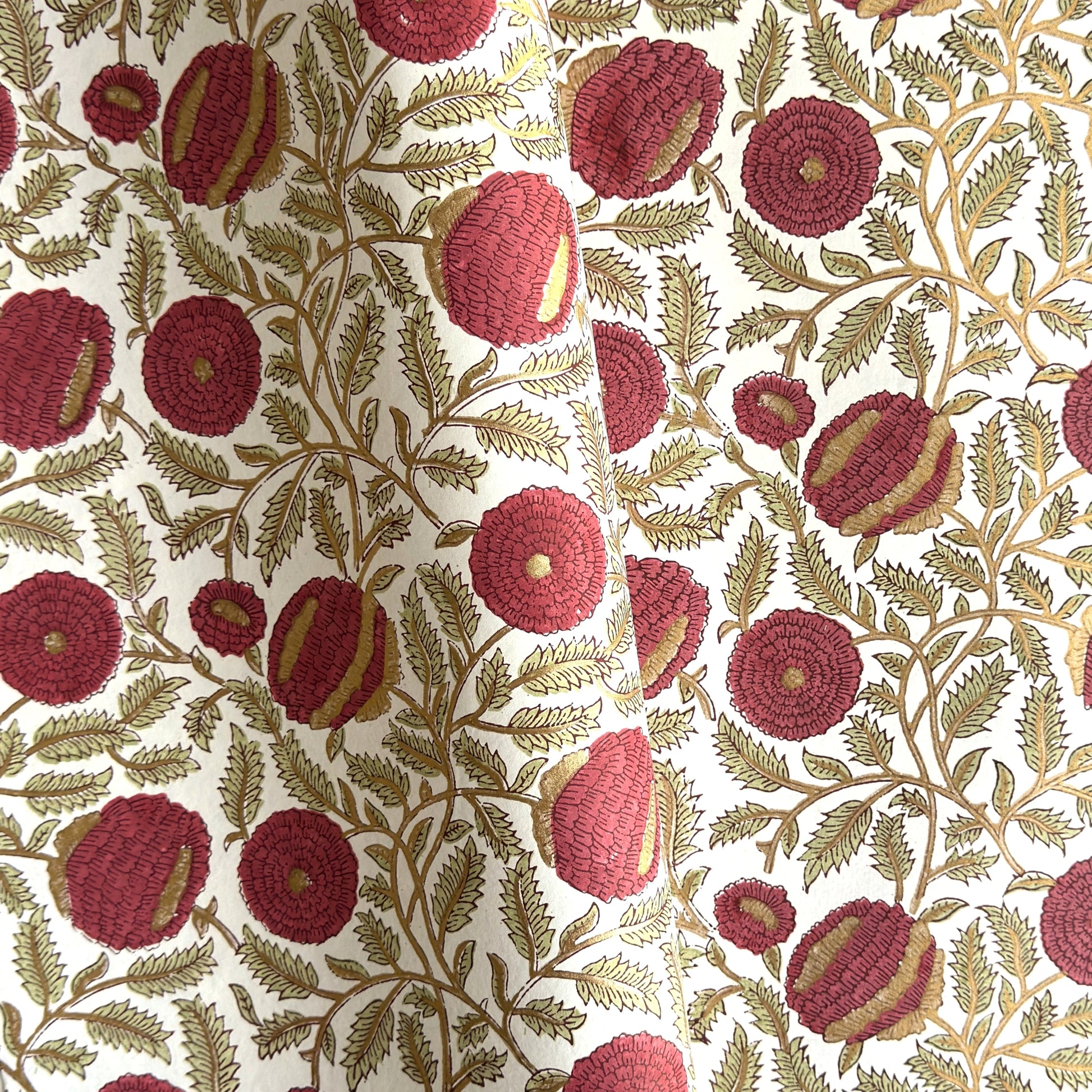 hand block printed paper by Paper Mirchi.  A floral repeat pattern in deep burgundy, pale green and gold.