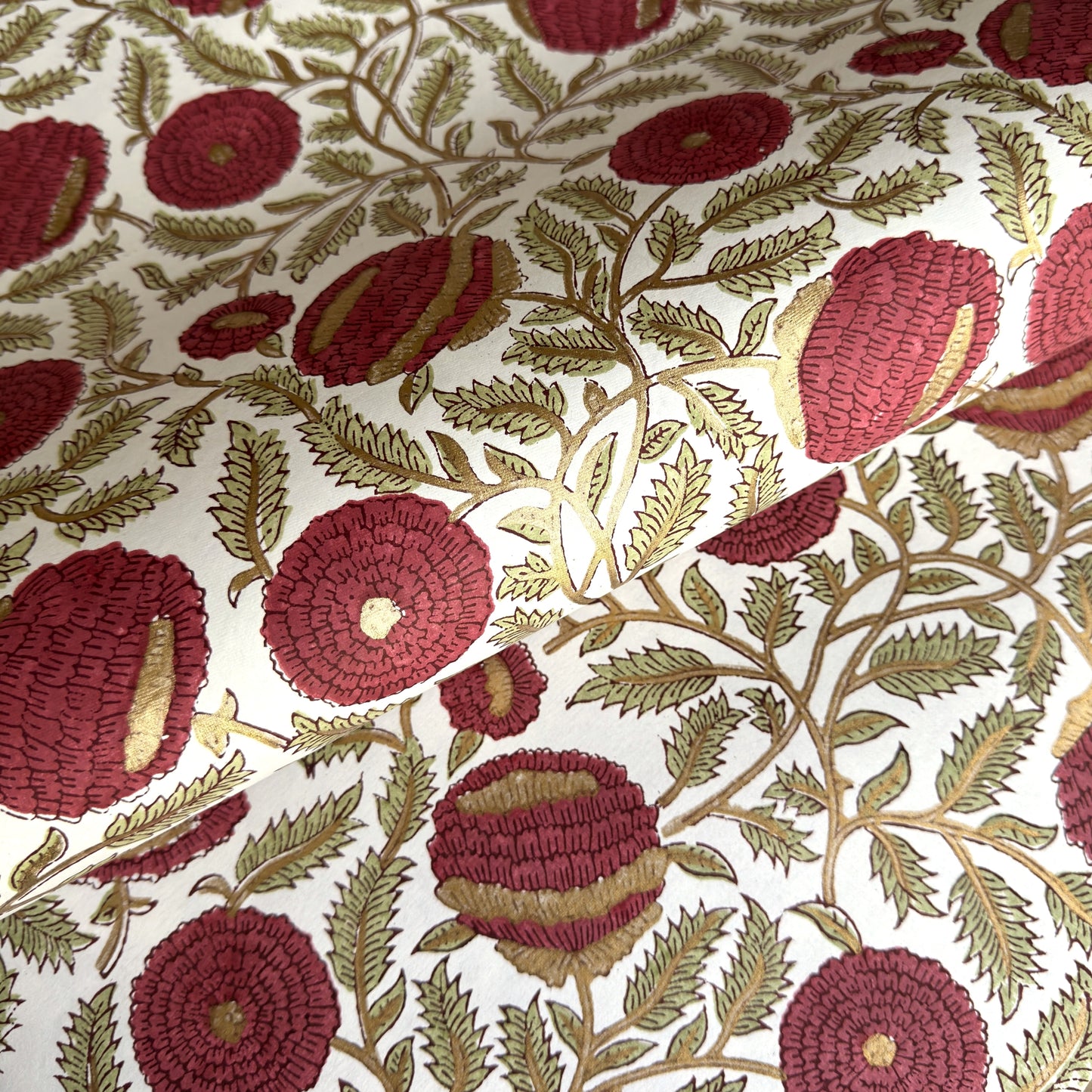 hand block printed paper by Paper Mirchi.  A floral repeat pattern in deep burgundy, pale green and gold.