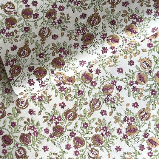Hand block printed wrapping paper with a pattern of pomegranates in cherry red, green and gold.