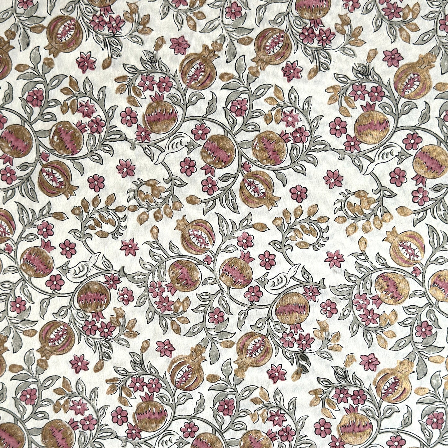 hand block printed wrapping paper by Paper Mirchi.  Repeat pattern of pomegranates in pink and green within a gold accent design.