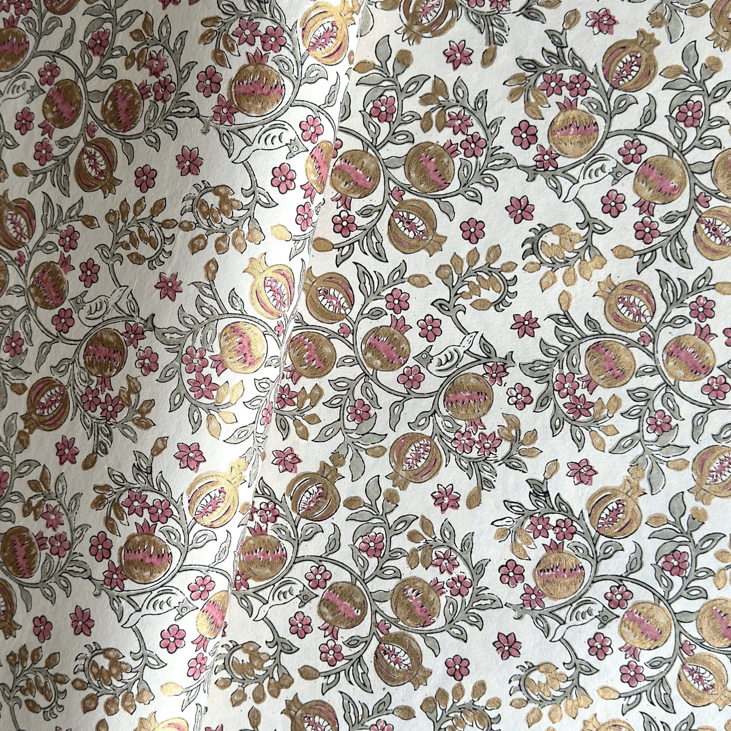 hand block printed wrapping paper by Paper Mirchi.  Repeat pattern of pomegranates in pink and green within a gold accent design.