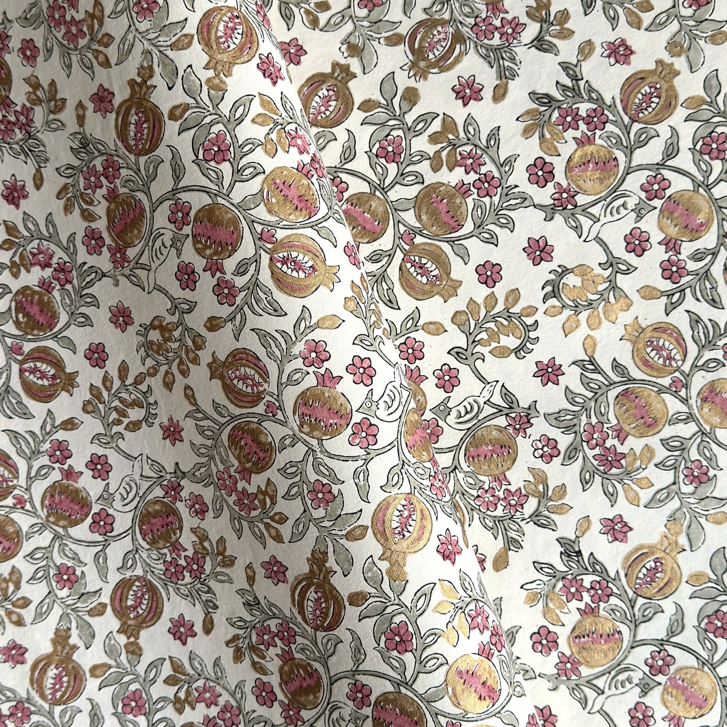 hand block printed wrapping paper by Paper Mirchi.  Repeat pattern of pomegranates in pink and green within a gold accent design.