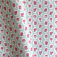 a sheet of hand block printed wrapping paper with a ditsy floral pattern of pink flowers in white ovals with a soft blue backdrop