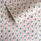 a sheet of hand block printed paper with a ditsy floral design, little violet flowers in a white oval with a pink background