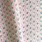 a sheet of hand block printed paper with a ditsy floral design, little violet flowers in a white oval with a pink background