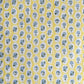 a sheet of hand block printed wrapping paper with a ditsy floral pattern of blue flowers in white ovals with a soft yellow backdrop  