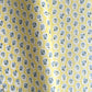 a sheet of hand block printed wrapping paper with a ditsy floral pattern of blue flowers in white ovals with a soft yellow backdrop  
