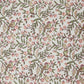 a sheet of hand-block printed wrapping paper with a pattern of a songbird amongst flowering branches in blush pink, soft green and gold