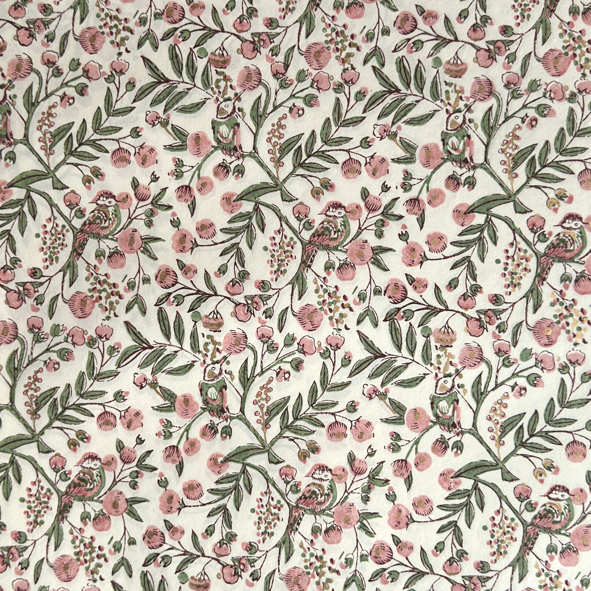 a sheet of hand-block printed wrapping paper with a pattern of a songbird amongst flowering branches in blush pink, soft green and gold