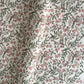 a sheet of hand-block printed wrapping paper with a pattern of a songbird amongst flowering branches in blush pink, soft green and gold