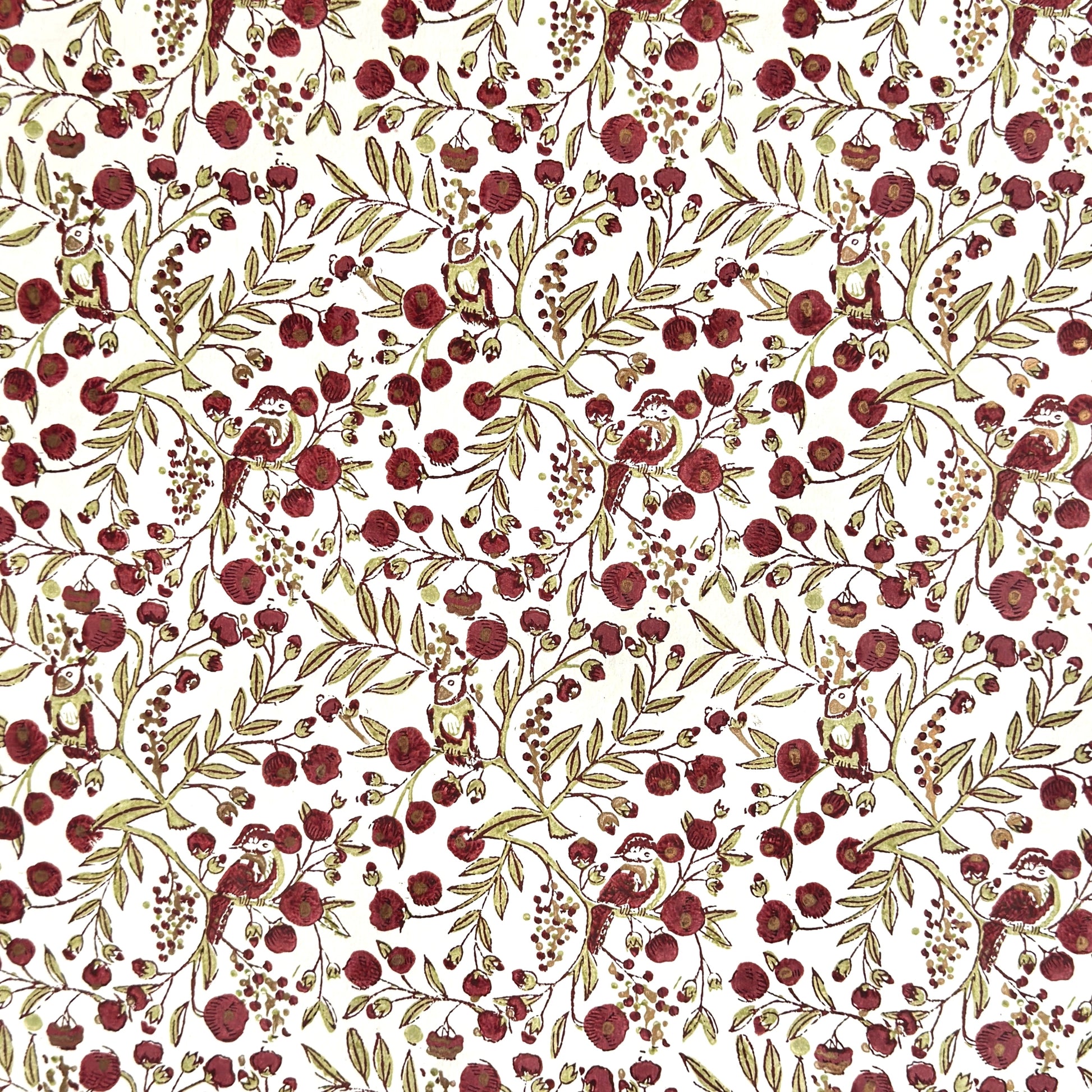 a sheet of hand block printed paper with a repeat pattern of foliage, flowers and a songbird in red, green and gold  