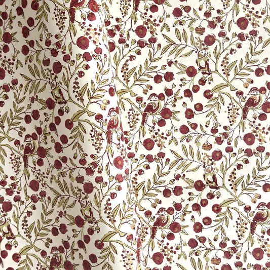 a sheet of hand block printed paper with a repeat pattern of foliage, flowers and a songbird in red, green and gold  