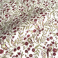 a sheet of hand block printed paper with a repeat pattern of foliage, flowers and a songbird in red, green and gold  