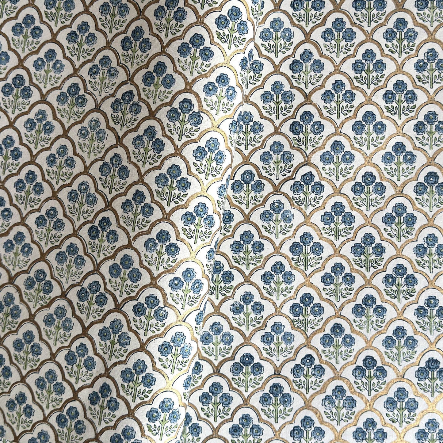 hand block printed wrapping paper with a small flower design in indigo and green surrounded by a gold trellis design. By Paper Mirchi