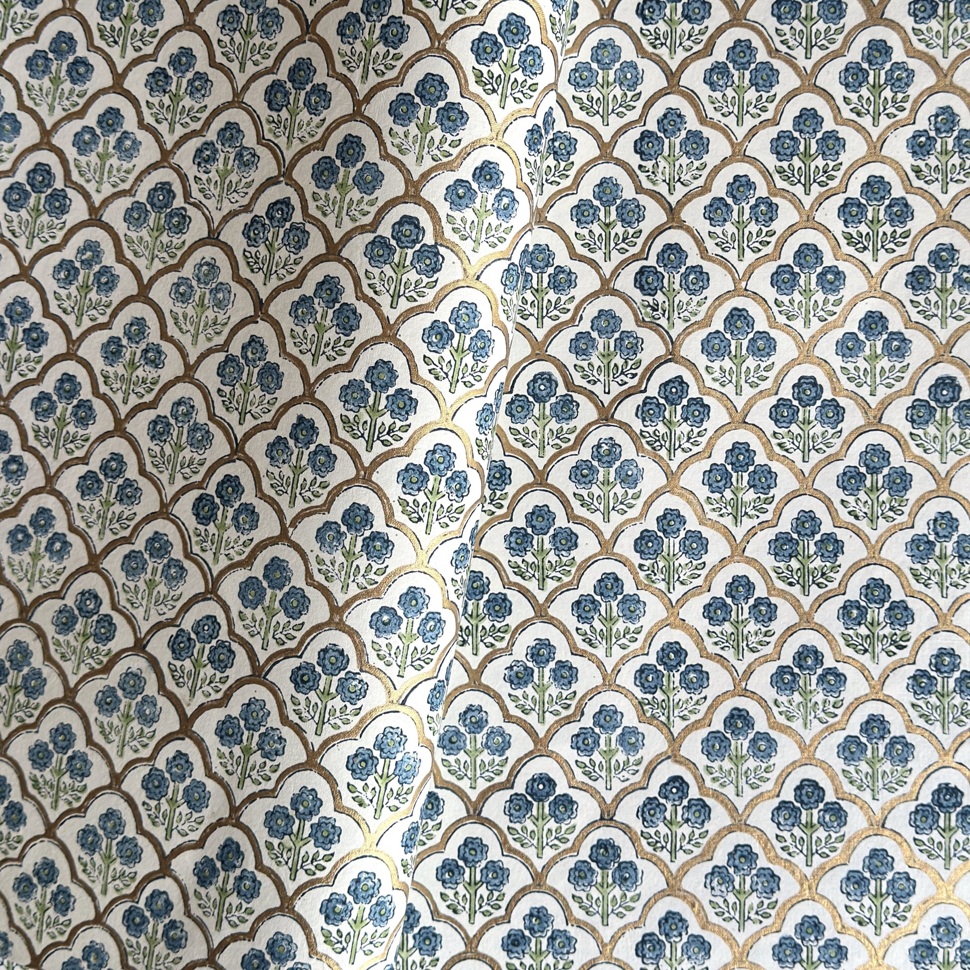 hand block printed wrapping paper with a small flower design in indigo and green surrounded by a gold trellis design. By Paper Mirchi