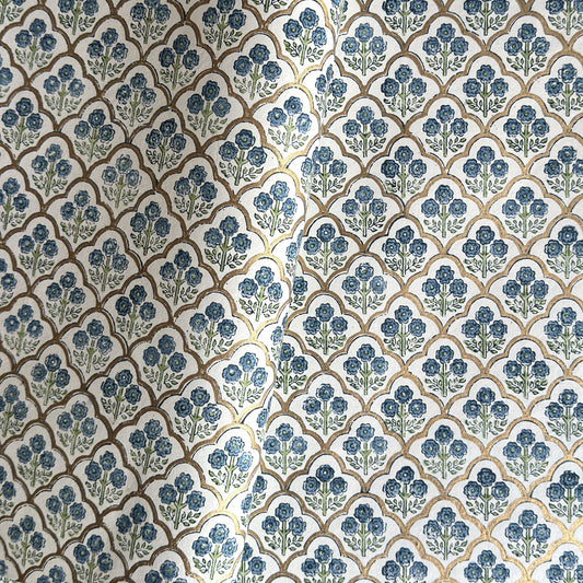 hand block printed wrapping paper with a small flower design in indigo and green surrounded by a gold trellis design. By Paper Mirchi