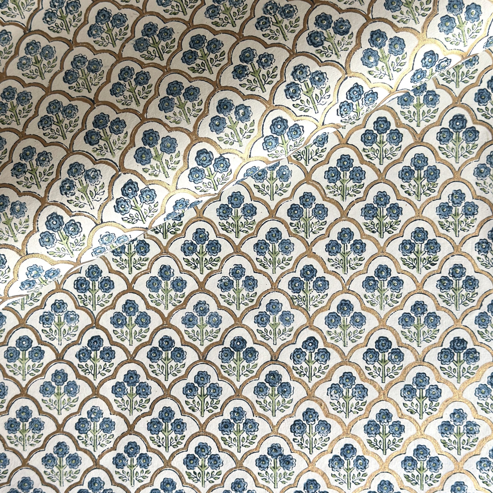 hand block printed wrapping paper with a small flower design in indigo and green surrounded by a gold trellis design. By Paper Mirchi