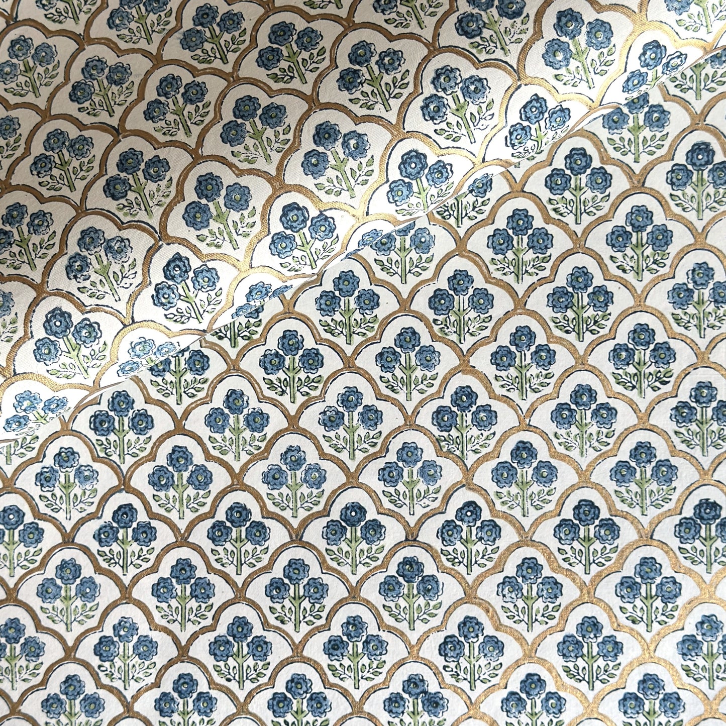 hand block printed wrapping paper with a small flower design in indigo and green surrounded by a gold trellis design. By Paper Mirchi
