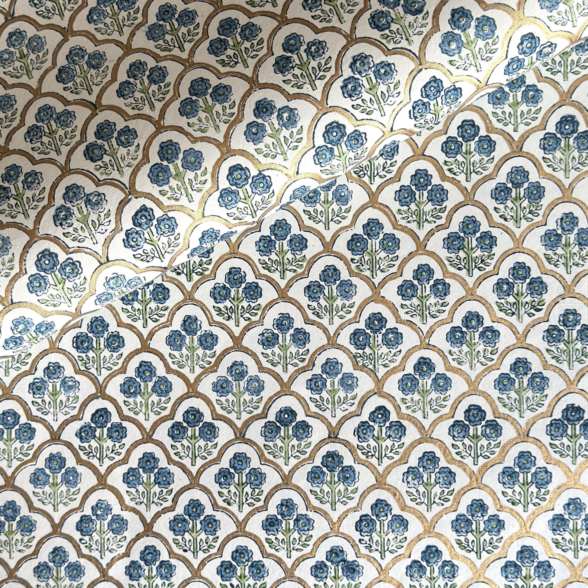 hand block printed wrapping paper with a small flower design in indigo and green surrounded by a gold trellis design. By Paper Mirchi