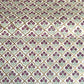 Hand block printed wrapping paper with a trellis pattern with flowers in cherry red, green and gold.